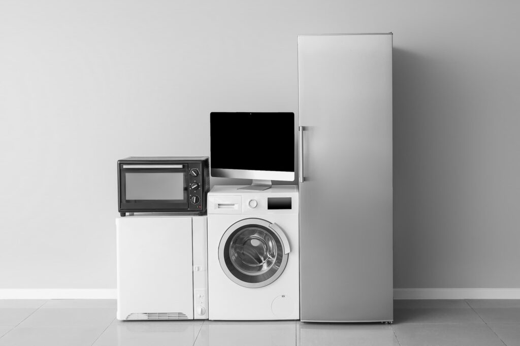 A collection of household appliances, including a fridge-freezer, washing machine, computer monitor and microwave.