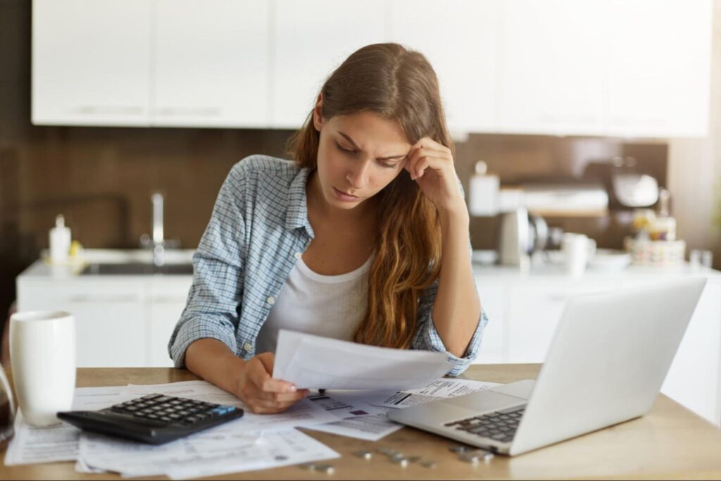 A woman reads her energy bills with a frown.