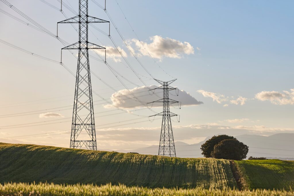 A series of electrical pylons crossing the countryside on a sunny day.